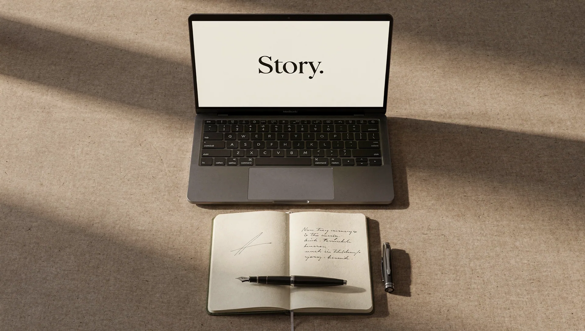 Laptop displaying Story beside a notebook and fountain pen in soft morning light